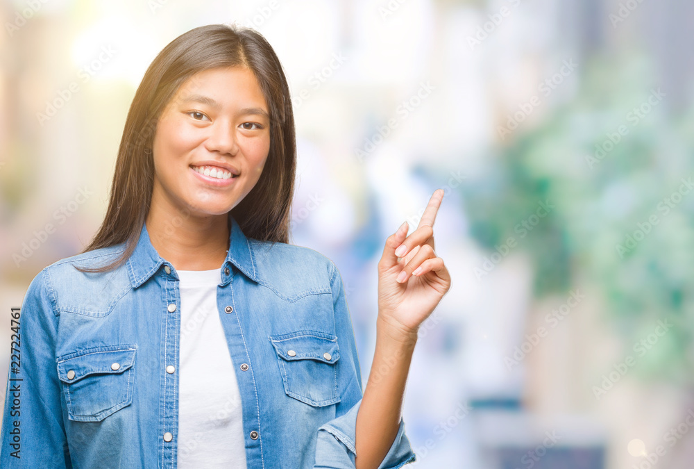 Young asian woman over isolated background with a big smile on face, pointing with hand and finger to the side looking at the camera. Young asian woman over isolated background with a big smile on face, pointing with hand and finger to the side looking at the camera.