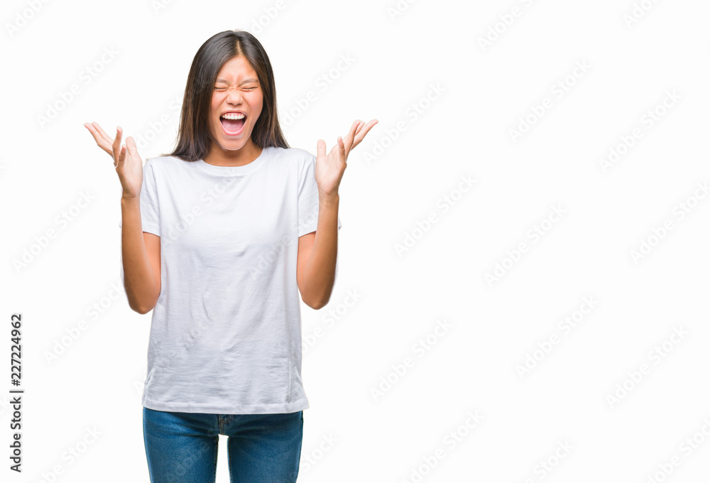 Young asian woman over isolated background celebrating mad and crazy for success with arms raised and closed eyes screaming excited. Winner concept Young asian woman over isolated background celebrating mad and crazy for success with arms raised and closed eyes screaming excited. Winner concept