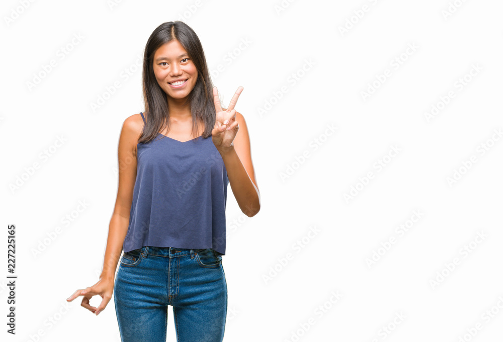Young asian woman over isolated background smiling with happy face winking at the camera doing victory sign. Number two. Young asian woman over isolated background smiling with happy face winking at the camera doing victory sign. Number two.