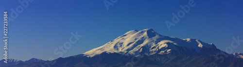 Mount Elbrus at dawn. Panoramic view of the sunlit slopes of the volcano from the northwest. North Caucasus in Russia.