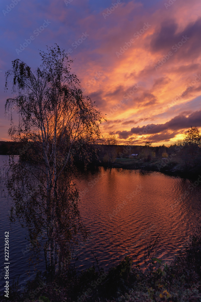 Obraz premium colorful sunset reflection into the calm water of a forest lake