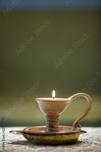 Lit candle in hand held ceramic candleholder, sand and green, relaxing, ambient, still photo