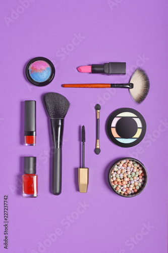 Top view on set of beauty products as decorative cosmetics and makeup brushes on bright purple background