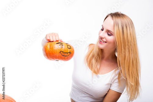 Halloween concept, happy Girl sitting at table with pumpkins preparing for holiday with candle and rope, holding Jack lantern, funny and spooky pumpkin. Trick or treat tradition