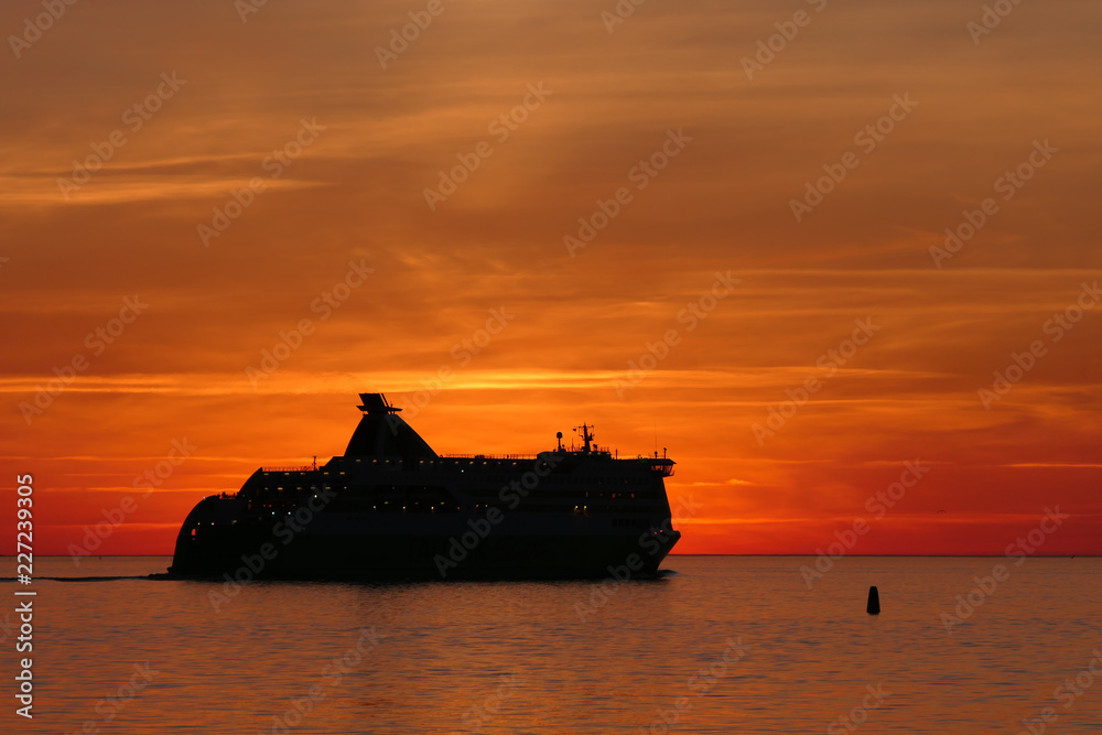 Heavenly - travel by ship in the evening sky. A ferry leaves the harbor and goes out into the sunset. The whole picture is marked by the sunset of the sun. 