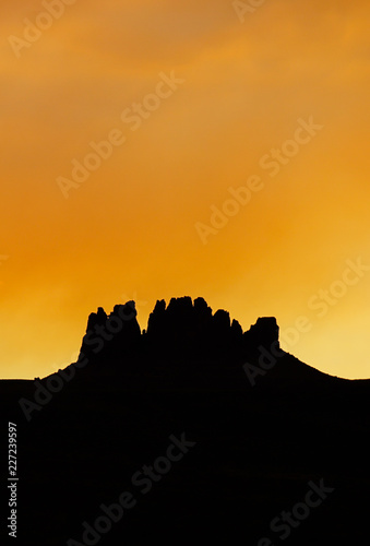 vertical rock mesa silhouette under an orange sunset sky in the northern Arizona desert