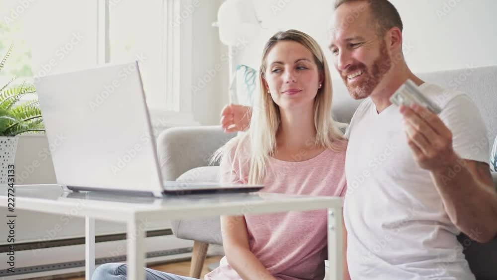 Excited young couple shopping online, holding credit card and looking at laptop at home Excited young couple shopping online, holding credit card and looking at laptop at home