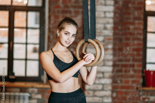 Sports girl doing stretching in the gym with rings Stands and smiles, holding on to the rings, rest in training. Professional equipment and clothing