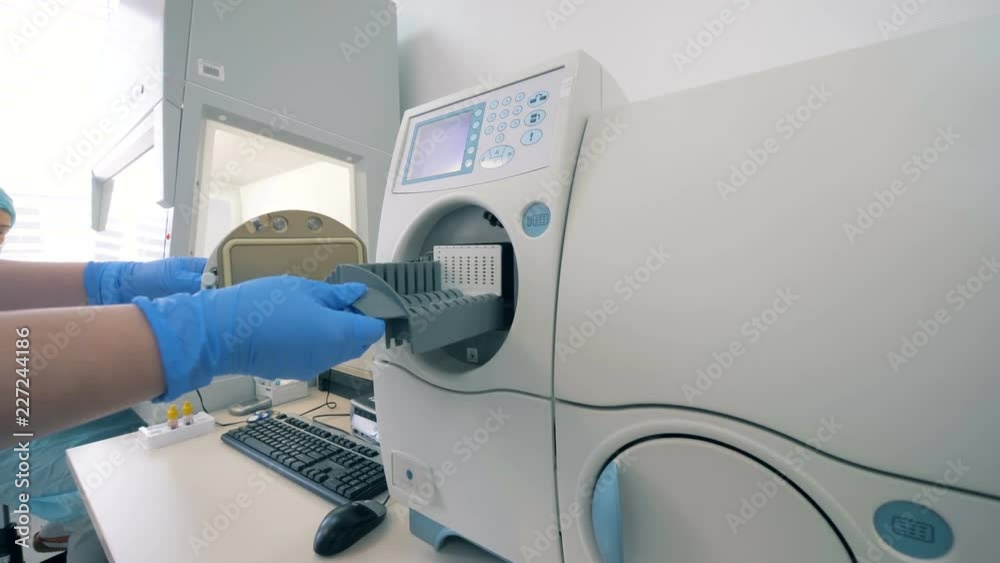 Laboratory worker loads the machine in a laboratory room. Laboratory worker loads the machine in a laboratory room.