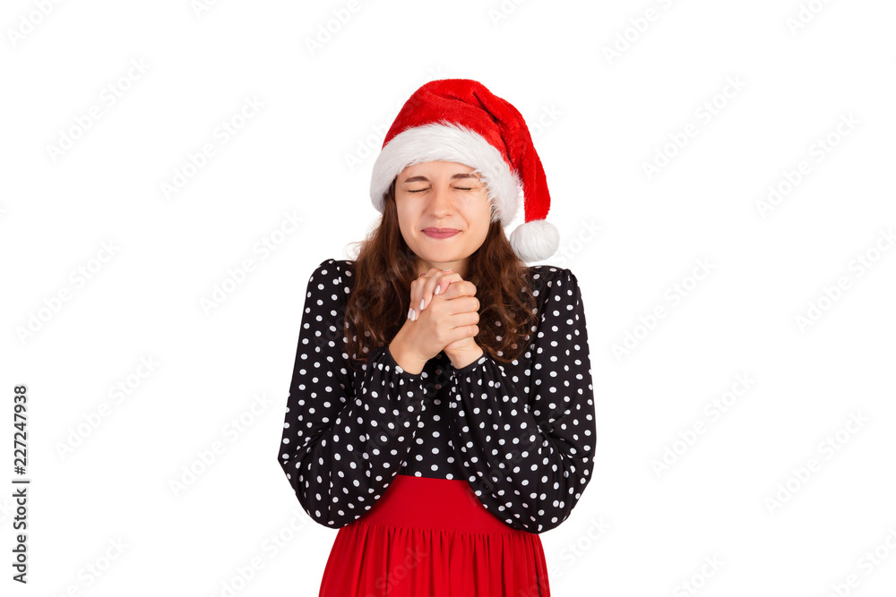 sympathizing woman in dress holding hands together on chest. emotional girl in santa claus christmas hat isolated on white background. holiday concept sympathizing woman in dress holding hands together on chest. emotional girl in santa claus christmas hat isolated on white background. holiday concept