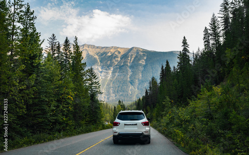 A white car running on a road with beautiful scenery