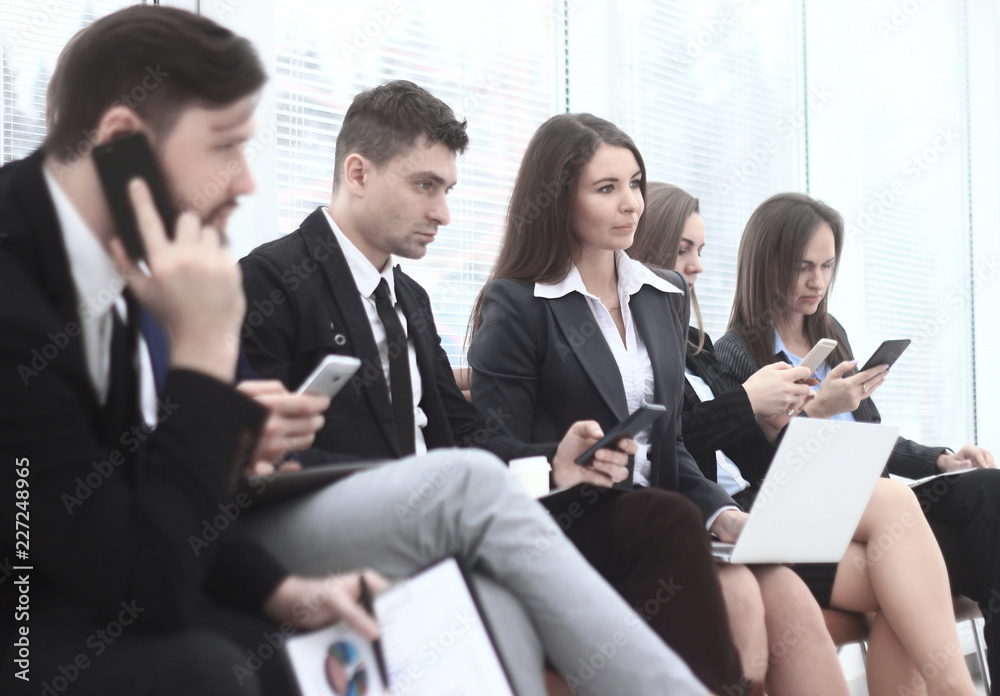group of young business people use laptops and smartphones while sitting in the office lobby group of young business people use laptops and smartphones while sitting in the office lobby