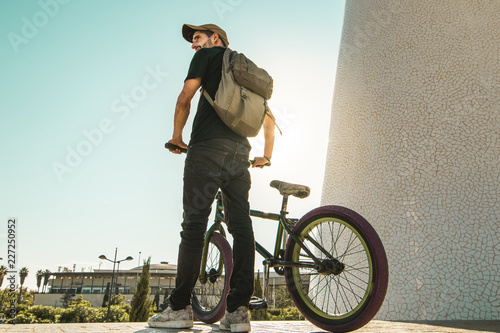 Young man with a bmx bike and a backpack in the city