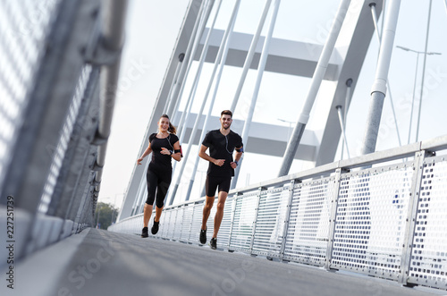 Wallpaper Mural Young couple doing morning workout outdoors. Young man and woman running on bridge. Torontodigital.ca