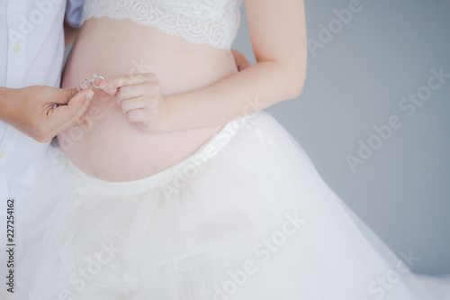 An Expecting parents holding wedding ring. pregnant woman