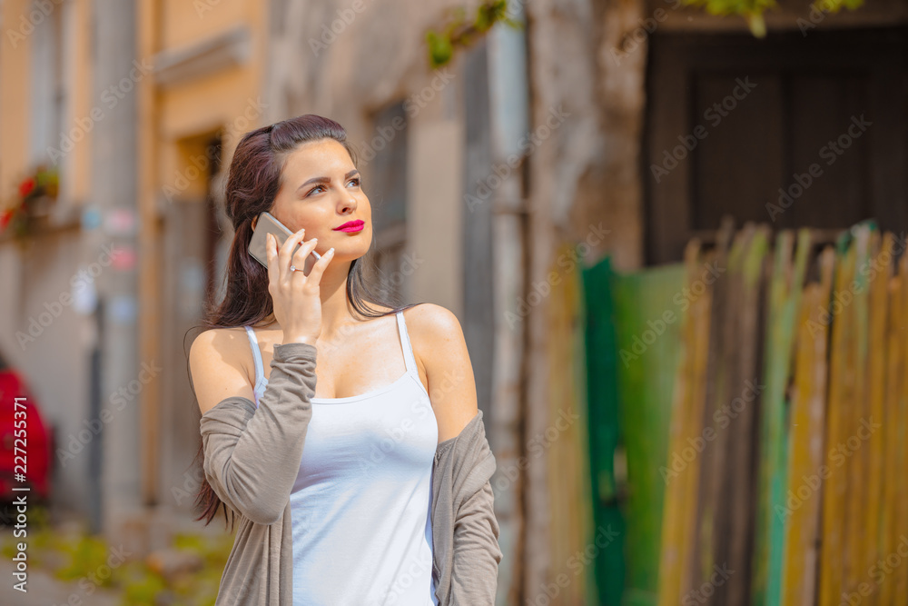 Cute young woman using cellphone in urban surroundings. Cute young woman using cellphone in urban surroundings.