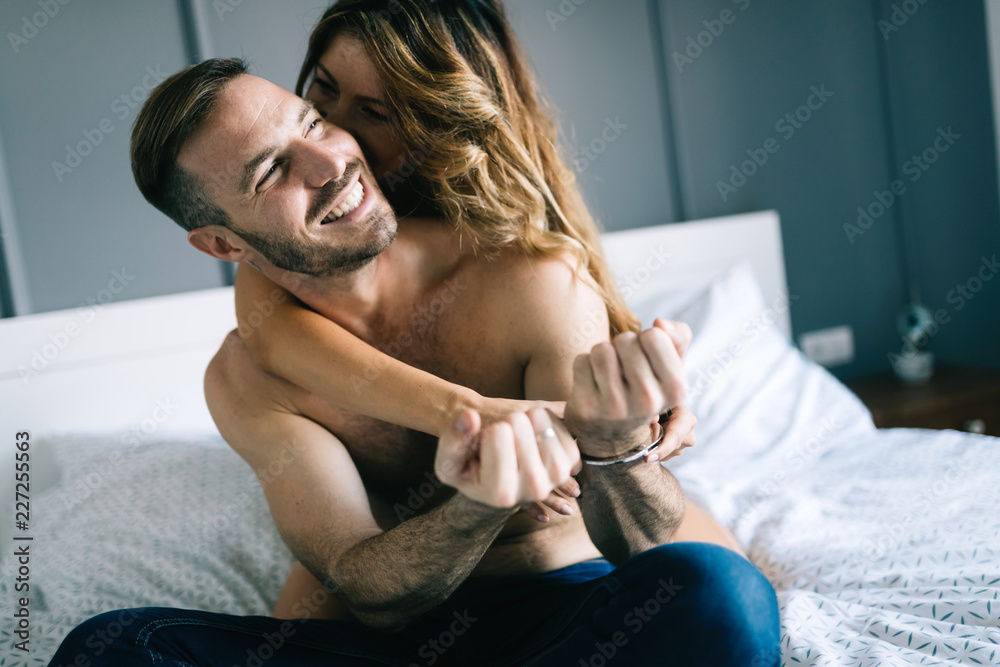 Fototapeta Widok kobiety w czarne majtki, trzymając jej stanik z tyłu, podczas gdy mężczyzna leży na łóżku