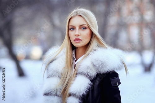 Young woman in fur coat standing outside