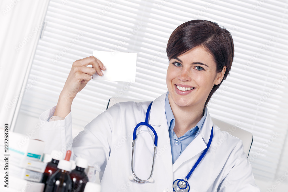 Smiling female doctor holding a business card or white pill box pack Smiling female doctor holding a business card or white pill box pack