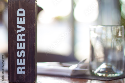 Reserved wooden Card Plate on the Table with Blurry background. Reservation Seat at restaurant. - leisure, people and service concept © Наталия Кузина