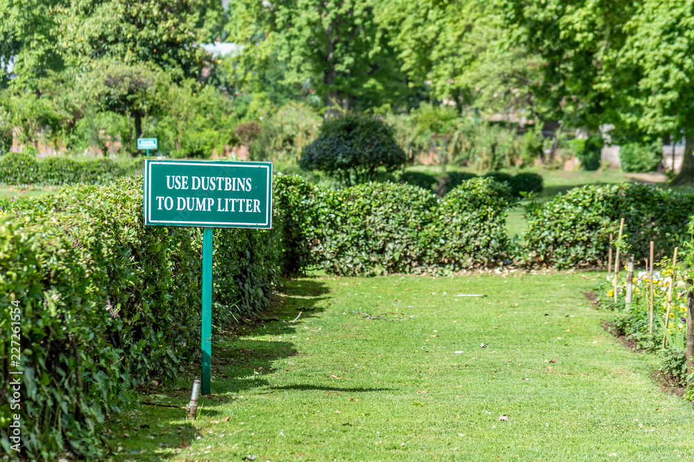 A sign board in a park encouraging the use of dustbins and do not litter