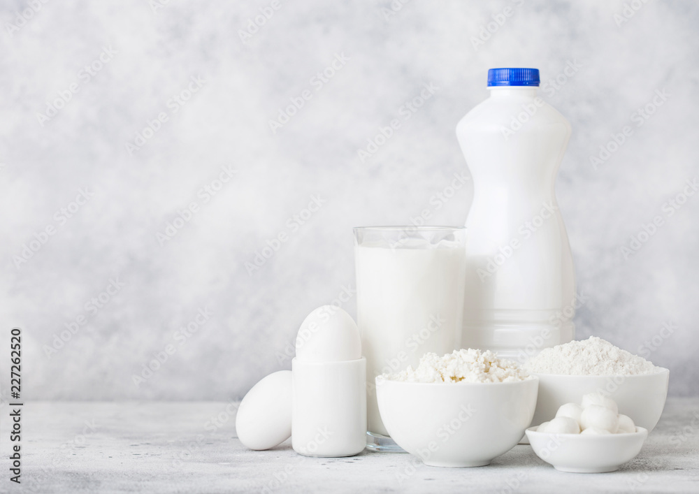 Fresh dairy products on white table background. Plastic bottle and glass of milk, bowl of cottage cheese and baking flour and mozzarella. Eggs and cheese. Fresh dairy products on white table background. Plastic bottle and glass of milk, bowl of cottage cheese and baking flour and mozzarella. Eggs and cheese.