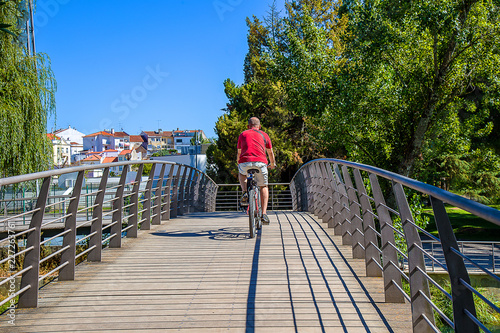 Man Ridding a Bike on a Public Park Bridge