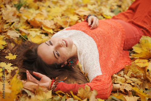 Happy woman autumn portrait, lying in autumn leaves