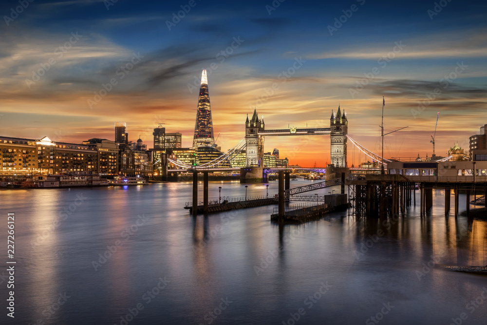 Blick auf die Tower Bridge an der Themse und die beleuchtete, urbane Skyline von London bei Sonnenuntergang, Großbritannien