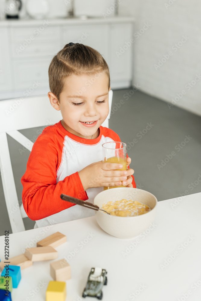 portrait of child with glass of juice having breakfast in kitchen at home portrait of child with glass of juice having breakfast in kitchen at home