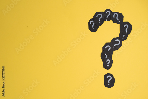 heap of black paper card with QUESTION MARK forming a question mark on bright yellow background. Concept of FAQ, Q&A, Problems and Questions