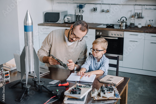 father and son repairing microcircuit at home photo