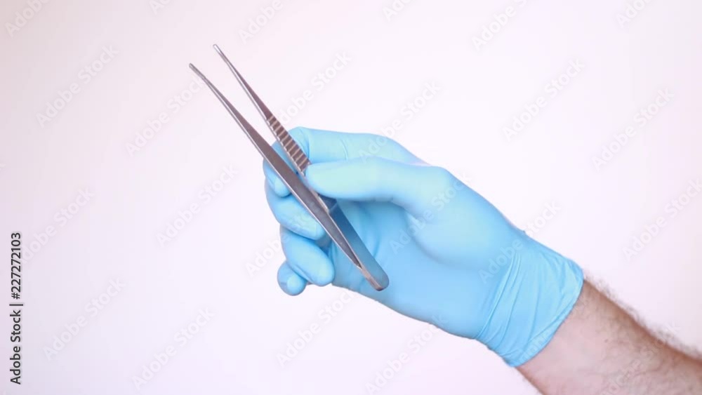 Tweezers in male hand dressed in latex glove Tweezers in male hand dressed in latex glove
