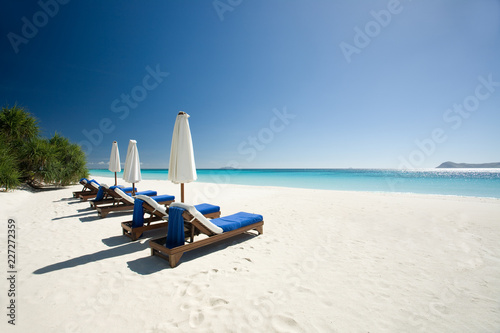 Luxury sunbeds on deserted white tropical private beach, turqouise blue chrystal clear waters © Ami