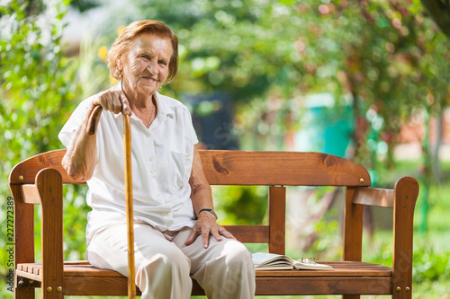 Elderly woman sitting and relaxing on a bench in park