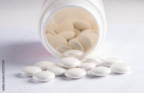 White round tablets covered with a cover are scattered from a plastic can with themWhite round tablets covered with a cover are scattered from a plastic can with them