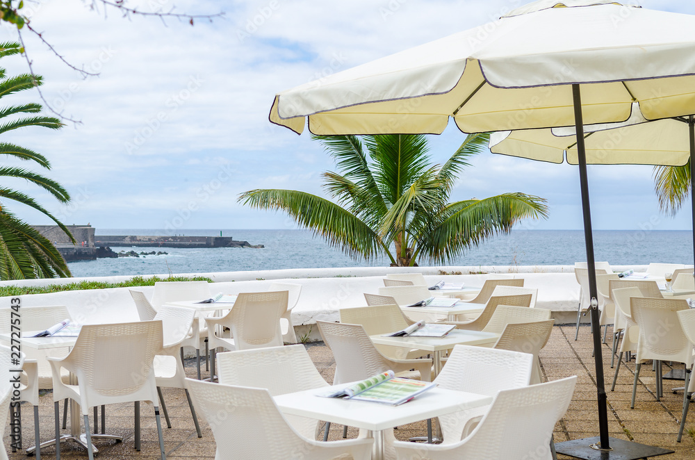 white restaurant tables on a terrace in front of the ocean