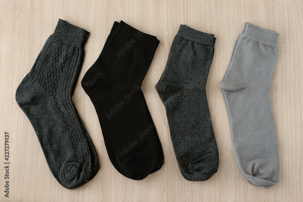 Men's classic socks. Black and gray men's socks on a wooden background. View from above. Clothing in the form of classic socks. Men's classic socks. Black and gray men's socks on a wooden background. View from above. Clothing in the form of classic socks.