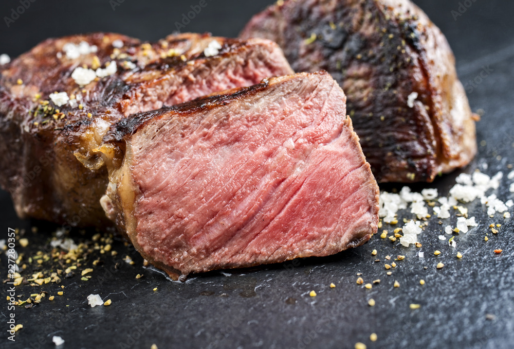 Traditional barbecue wagyu roast beef sliced as top view on a black board Traditional barbecue wagyu roast beef sliced as top view on a black board