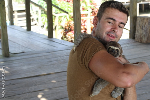 Fototapeta Naklejka Na Ścianę i Meble -  Tender man taking care of a sloth 