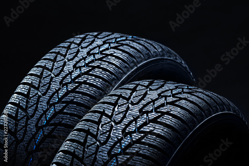 Set of new winter tires on black background with contrasty lighting. Close up product photograph of unused tyres photo