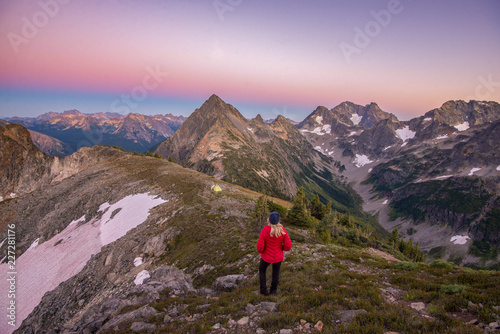 A woman in the mountains looking at valley view with tent in the background