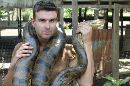 Strong man holding gigantic anaconda 