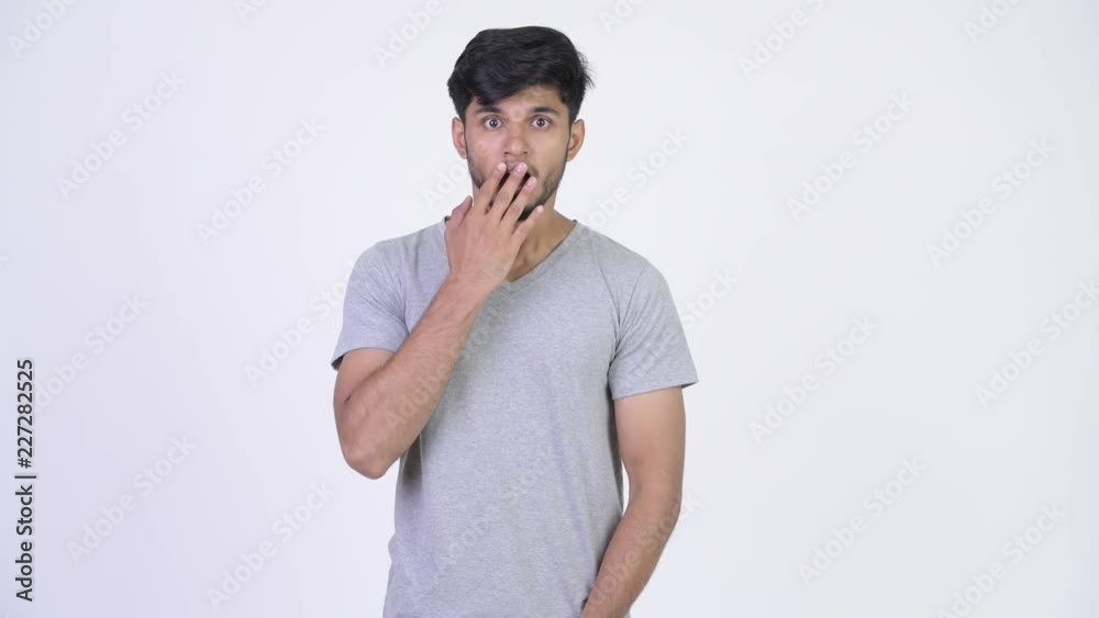 Young handsome bearded Indian man looking shocked Young handsome bearded Indian man looking shocked