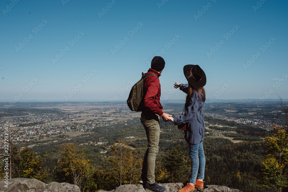 Young traveling couple holding hands at the top of the mountain