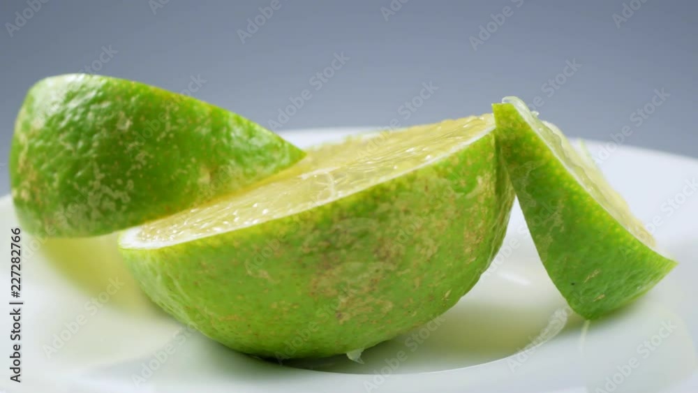 Fresh green lemon slice is slowly rotating in the studio with the details. Fresh green lemon slice is slowly rotating in the studio with the details.