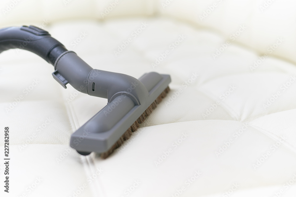 The vacuum cleaner brush is on the leather sofa. The vacuum cleaner brush is on the leather sofa.