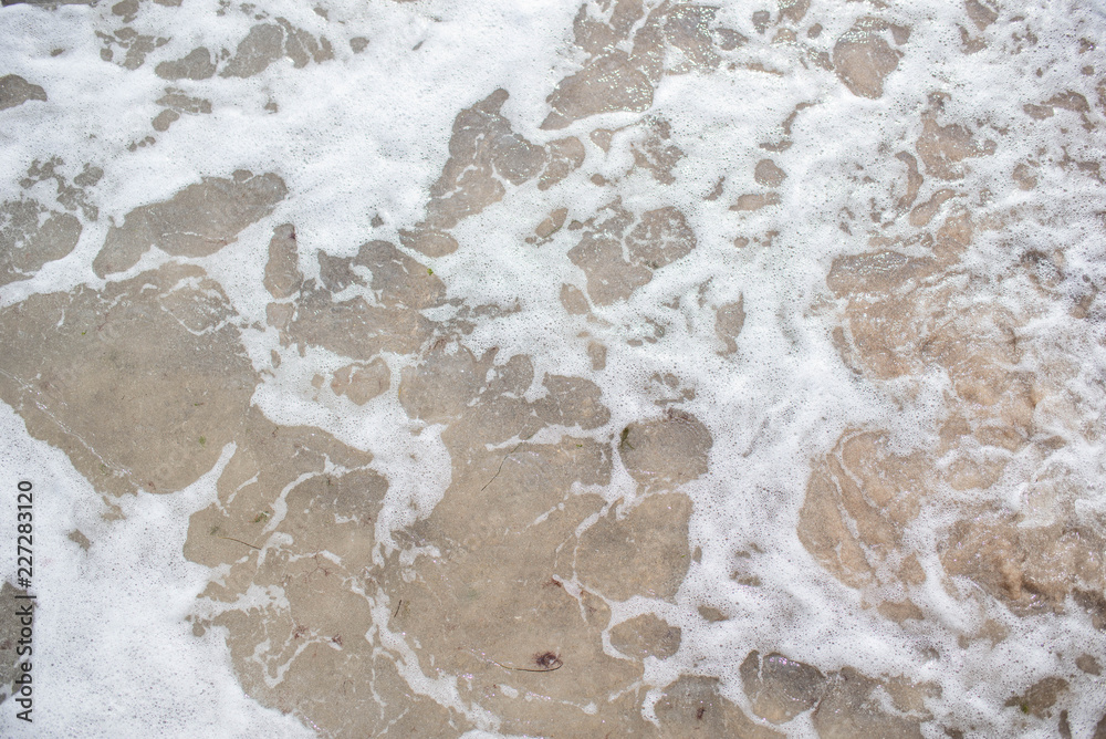 Unusual and very beautiful sea foam on the background of a sandy clean beach on a bright and sunny summer day Unusual and very beautiful sea foam on the background of a sandy clean beach on a bright and sunny summer day