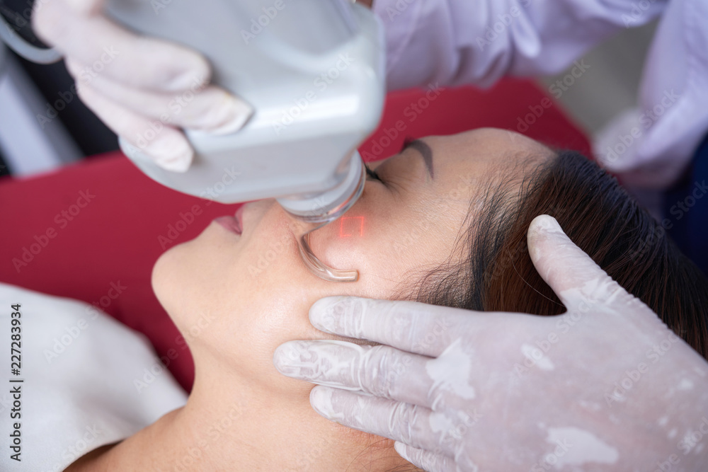 Attractive woman lying with eyes closed and getting a rejuvenating facial procedure with ultrasound equipment Attractive woman lying with eyes closed and getting a rejuvenating facial procedure with ultrasound equipment