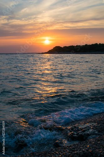Fototapeta Naklejka Na Ścianę i Meble -  A beautiful sunset on a beach with the waves of the Adriatic Sea hitting the coast of Croatia 